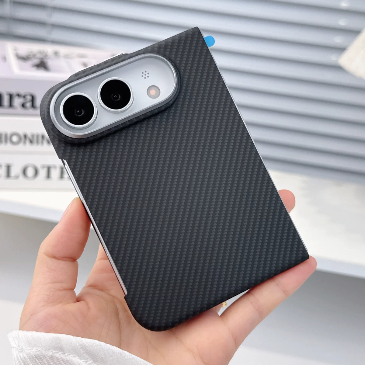 Black carbon fibre case on iPhone Duo, folded, held in hand